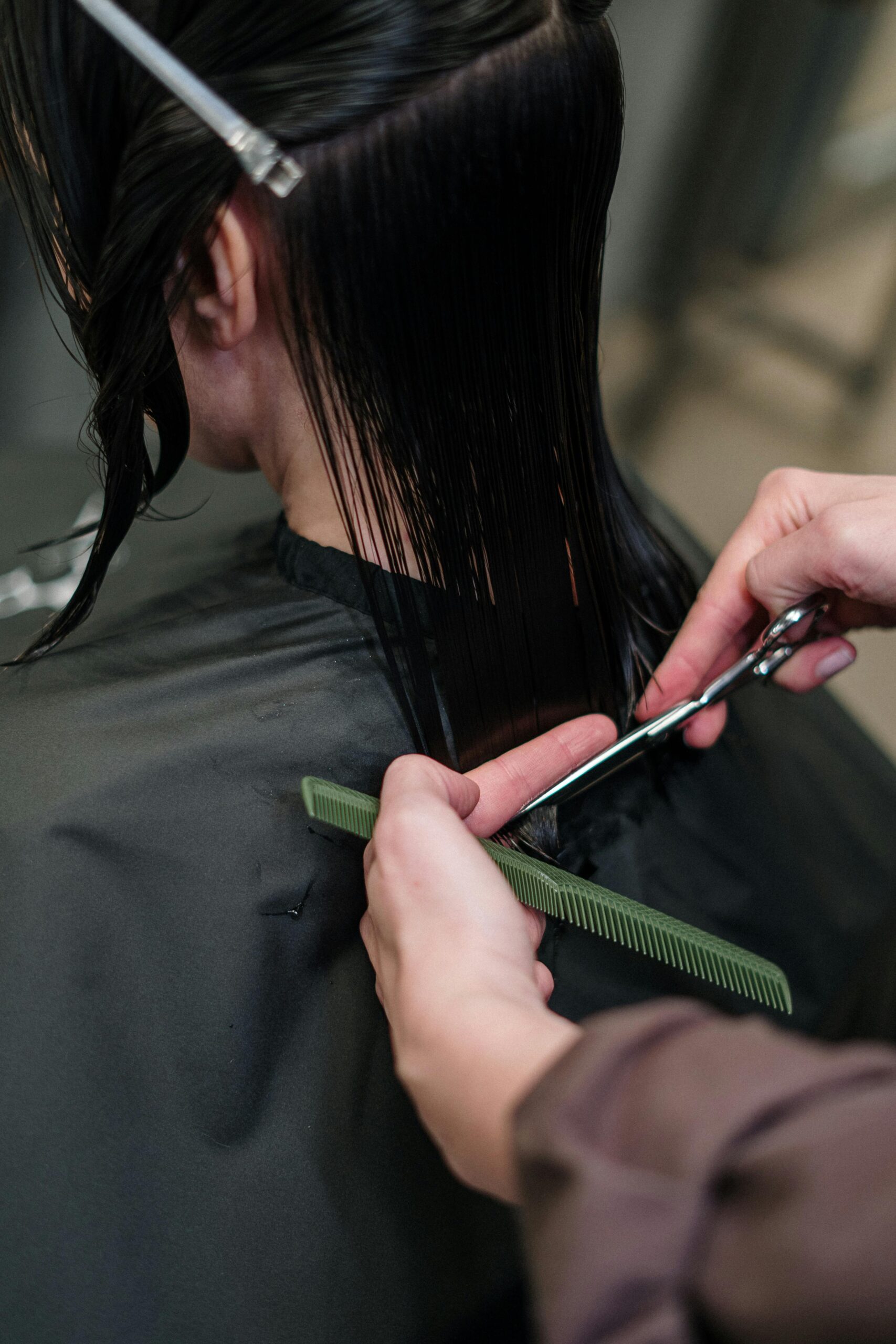 Profissionais Close-up of a hairstylist cutting a woman's hair in a salon, showcasing precise techniques.